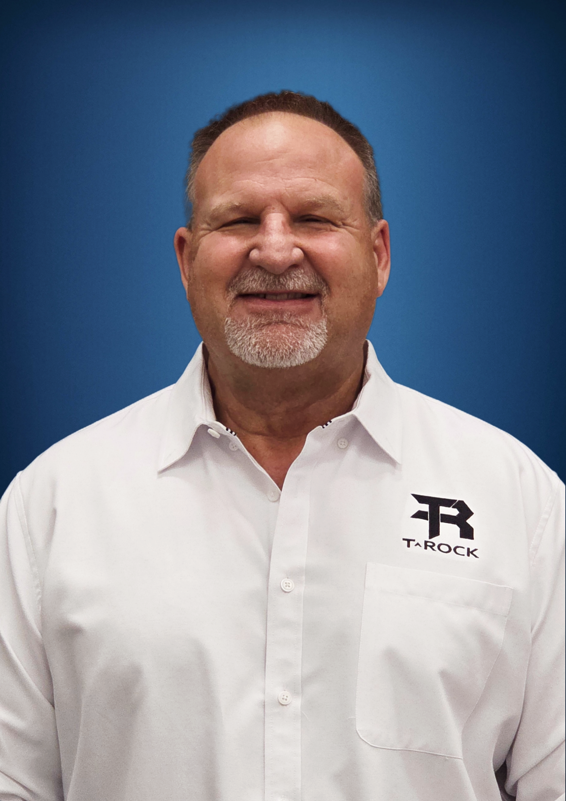 Smiling man in a white shirt with the Tarock logo on a blue background.